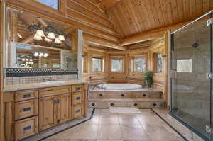 Primary bathroom with tile floors, rustic walls, plus walk in shower, and vanity