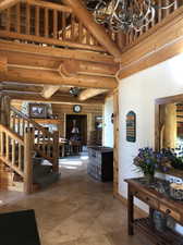 Interior space with a high ceiling, tile flooring, an inviting chandelier, and rustic walls