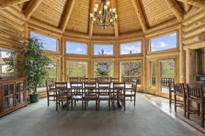 Dining space with high vaulted ceiling, an inviting chandelier, log walls, and wooden ceiling