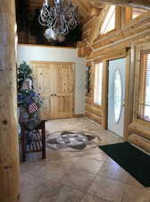 Entryway featuring a healthy amount of sunlight, a notable chandelier, tile flooring, and rustic walls