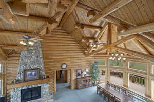 Interior space with a stone fireplace, wooden ceiling, beam ceiling, and rustic walls. Looking down from the upstairs balcony.