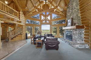 Carpeted living room with high vaulted ceiling, rustic walls, and wood ceiling