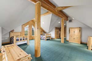 Carpeted bedroom featuring vaulted ceiling with beams