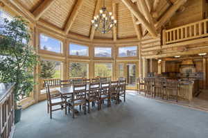 Dining area featuring carpet flooring, a notable chandelier, wooden ceiling, high vaulted ceiling, and beamed ceiling