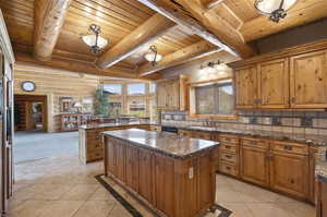 Kitchen featuring a kitchen island, tasteful backsplash, wooden ceiling, sink, and light tile floors