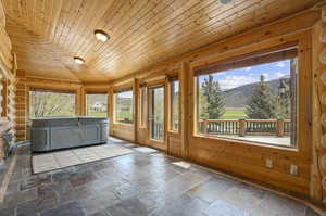 Sunroom featuring wooden ceiling and hot tub/spa