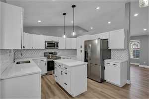 Kitchen featuring appliances with stainless steel finishes, light hardwood / wood-style floors, backsplash, and a kitchen island