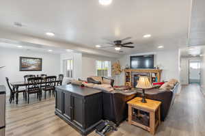 Apartment Living room with a brick fireplace, light wood-type flooring, and ceiling fan