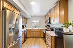 Apartment Kitchen with appliances with stainless steel finishes, sink, and light wood-type flooring