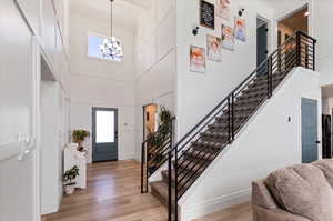 Foyer entrance with a towering ceiling, plenty of natural light, a chandelier, and light hardwood / wood-style flooring