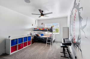 Carpeted bedroom featuring a textured ceiling and ceiling fan