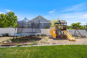 View of play area with a lawn and a trampoline