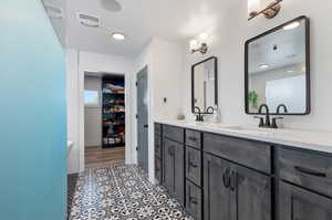 Bathroom featuring vanity with extensive cabinet space, double sink, and tile flooring