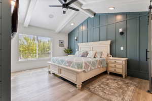 Bedroom featuring ceiling fan, lofted ceiling with beams, and hardwood / wood-style flooring