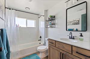 Apartment Full bathroom featuring shower / bath combo, a textured ceiling, toilet, and vanity