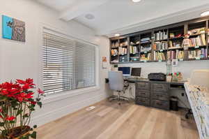 Office with beamed ceiling, built in desk, and light hardwood / wood-style flooring