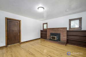 Unfurnished living room featuring light hardwood / wood-style flooring, a brick fireplace, and a healthy amount of sunlight