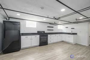 Kitchen with sink, white cabinetry, black appliances, and light hardwood / wood-style floors