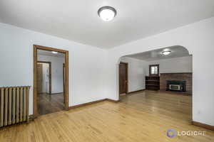 Unfurnished living room with radiator heating unit, a fireplace, and light hardwood / wood-style flooring