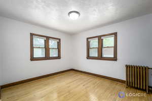 Unfurnished room featuring light hardwood / wood-style flooring and radiator heating unit