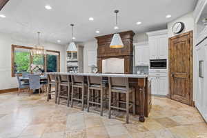 Kitchen featuring hanging light fixtures, stainless steel microwave, a large island, and tasteful backsplash