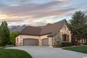 View of front facade with a garage, a mountain view, and a lawn