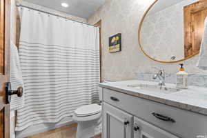 Full bathroom with toilet, tile floors, vanity, a textured ceiling, and shower / tub combo with curtain