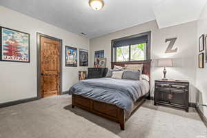 Bedroom featuring a textured ceiling and light colored carpet