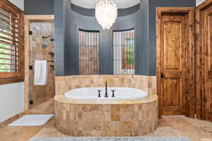 Bathroom featuring tile flooring, separate shower and tub, and an inviting chandelier