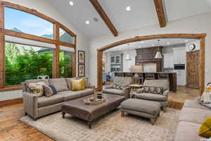 Living room featuring high vaulted ceiling, beam ceiling, and light hardwood / wood-style floors