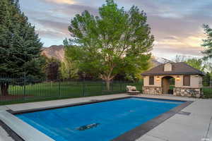 Pool at dusk featuring a yard, a mountain view, and a patio area