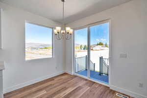 Unfurnished dining area featuring a textured ceiling, an inviting chandelier, and light hardwood / wood-style flooring