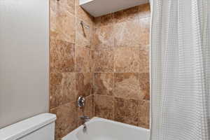 Bathroom featuring shower / bath combination with curtain and toilet