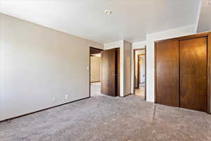 Unfurnished bedroom featuring light carpet and a closet