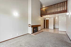 Unfurnished living room with light carpet and a towering ceiling