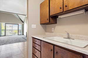 Kitchen featuring light colored carpet, sink, and lofted ceiling