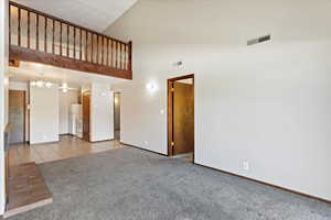 Interior space with light carpet, high vaulted ceiling, and an inviting chandelier