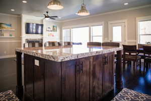 Kitchen featuring decorative light fixtures, ornamental molding, dark hardwood / wood-style floors, and dark brown cabinets