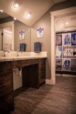 Bathroom featuring vaulted ceiling, vanity, hardwood / wood-style flooring, and a textured ceiling