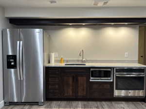 Kitchen with stainless steel appliances, hardwood / wood-style floors, sink, and dark brown cabinets