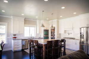 Kitchen with stainless steel appliances, a kitchen bar, plenty of natural light, and dark hardwood / wood-style floors