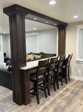 Bar with hardwood / wood-style flooring and dark brown cabinetry