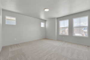 Empty room with light carpet and a textured ceiling