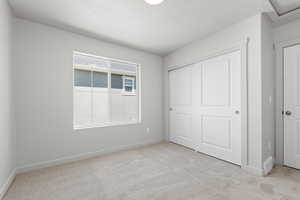 Unfurnished bedroom featuring light colored carpet and a closet