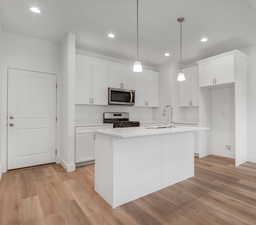 Kitchen featuring stainless steel appliances, white cabinets, and light wood-type flooring