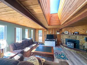 Living room featuring a fireplace, wooden ceiling, hardwood / wood-style flooring, a wood stove, and wood walls