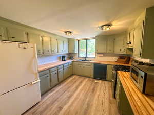 Kitchen with sink, black dishwasher, white refrigerator, and light wood-type flooring