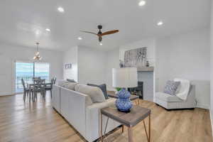 Living room with light hardwood / wood-style floors and ceiling fan with notable chandelier