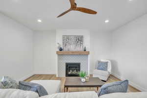 Living room with ceiling fan, light hardwood / wood-style flooring, and a fireplace