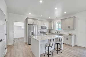 Kitchen with appliances with stainless steel finishes, light hardwood / wood-style floors, a kitchen island, and pendant lighting